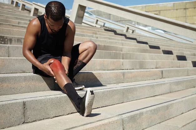 Young man holding his knee with an extremity injury — chiropractic care in Oakland